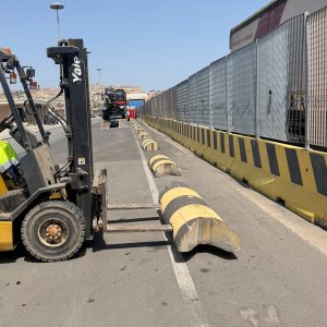 Posizionamento dissuasori nell'area portuale di Cagliari con un carrello elevatore guidato da un operatore che indossa indumenti di sicurezza ad alta visibilità.