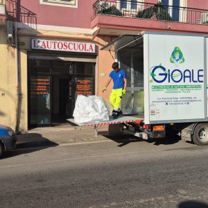 Operatore in divisa carica un grande sacco bianco nel retro del furgone