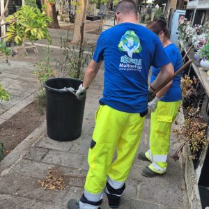 operatore in divisa che spazza il pavimento , pantaloni gialli alta visibilità e maglietta azzurra con logo aziendale